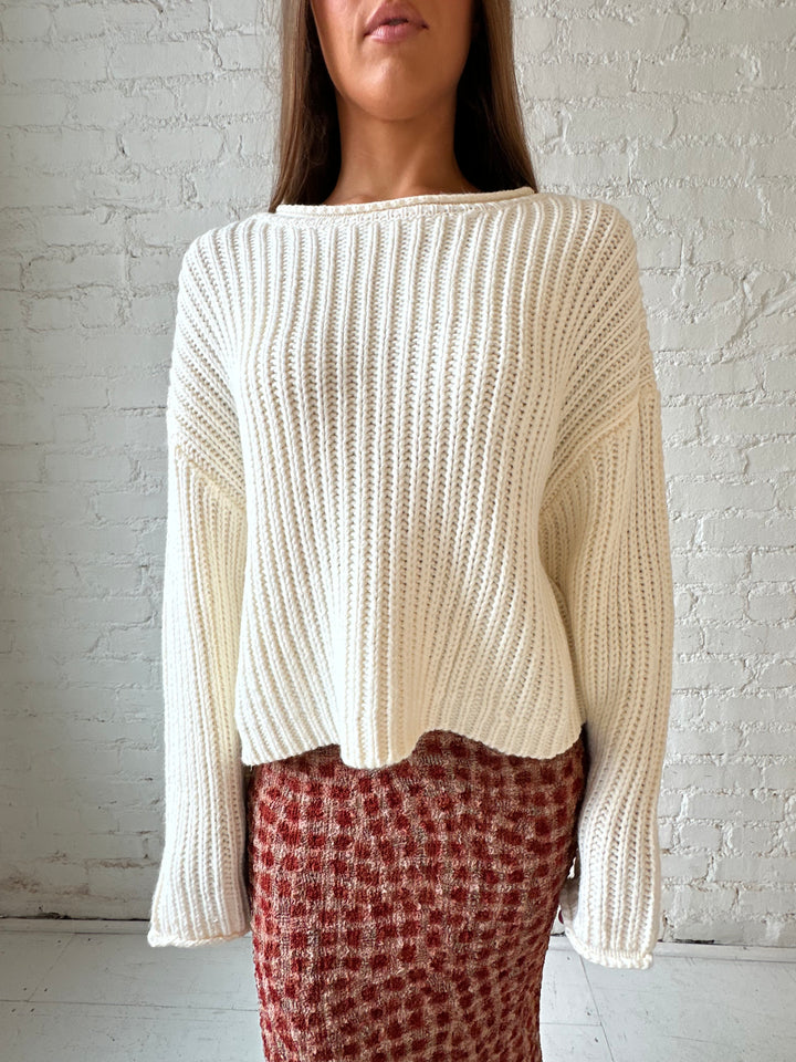 Woman wearing cream knit sweater with burgundy textured dotted maxi skirt.