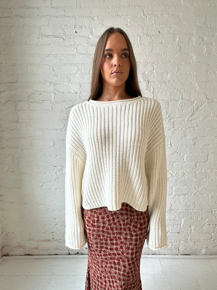 Woman wearing cream knit sweater with burgundy textured dotted maxi skirt.