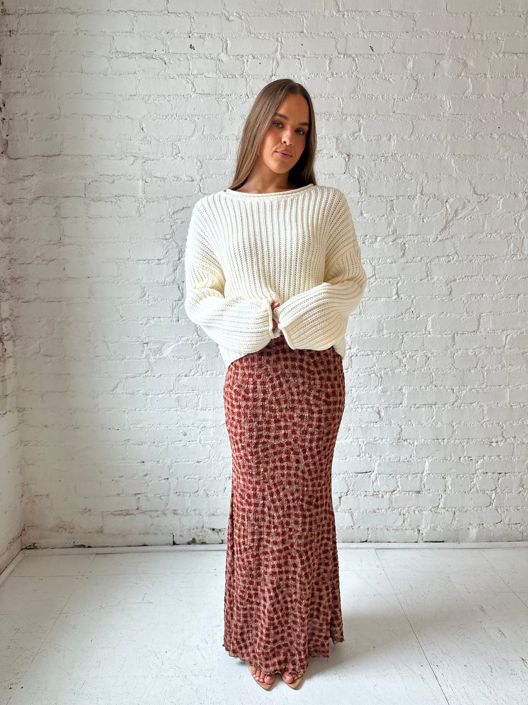 Woman wearing cream knit sweater with burgundy textured dotted maxi skirt.