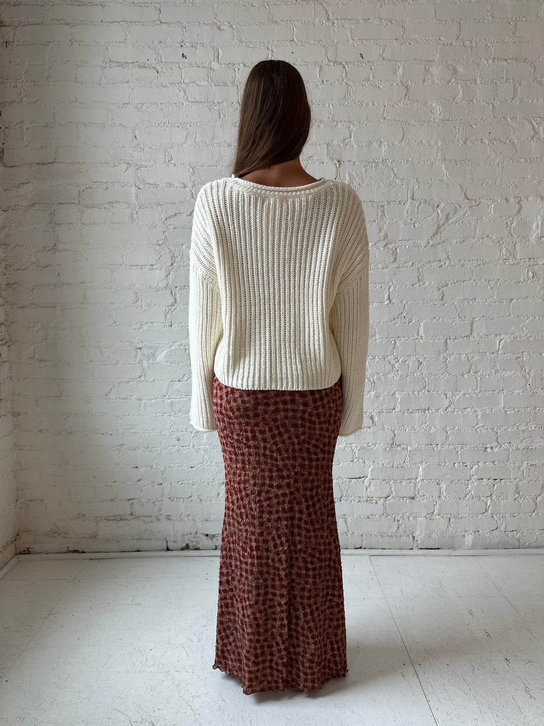 Woman wearing cream knit sweater with burgundy textured dotted maxi skirt.