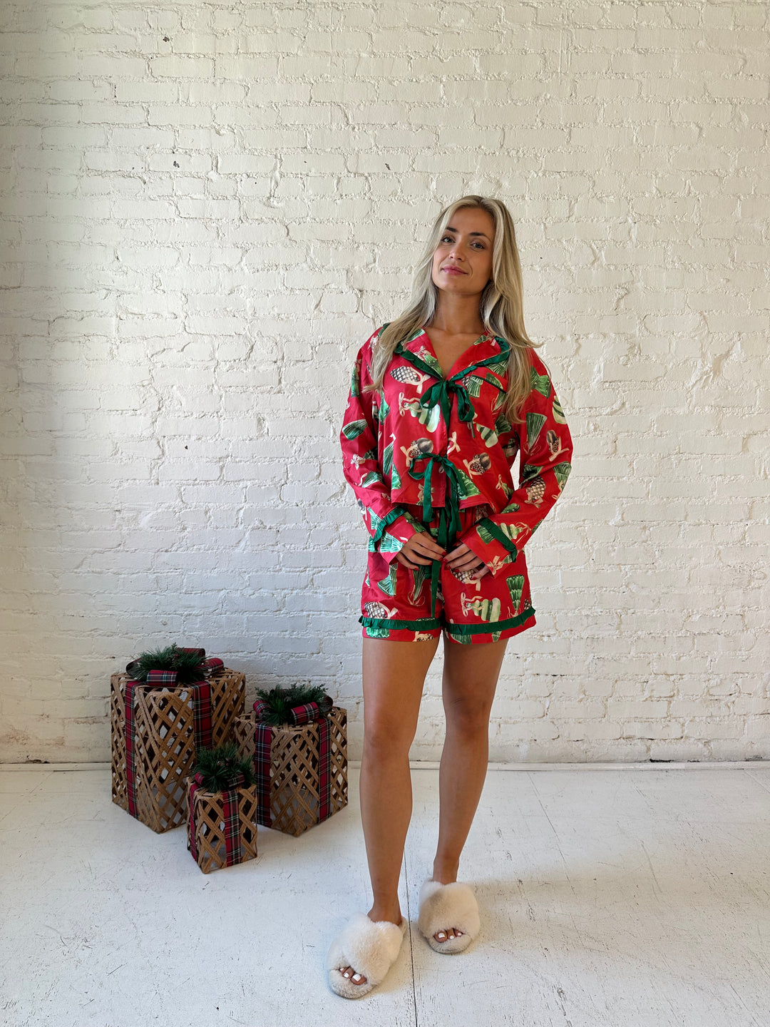 Woman wearing red satin pajama set with ornaments all over.
