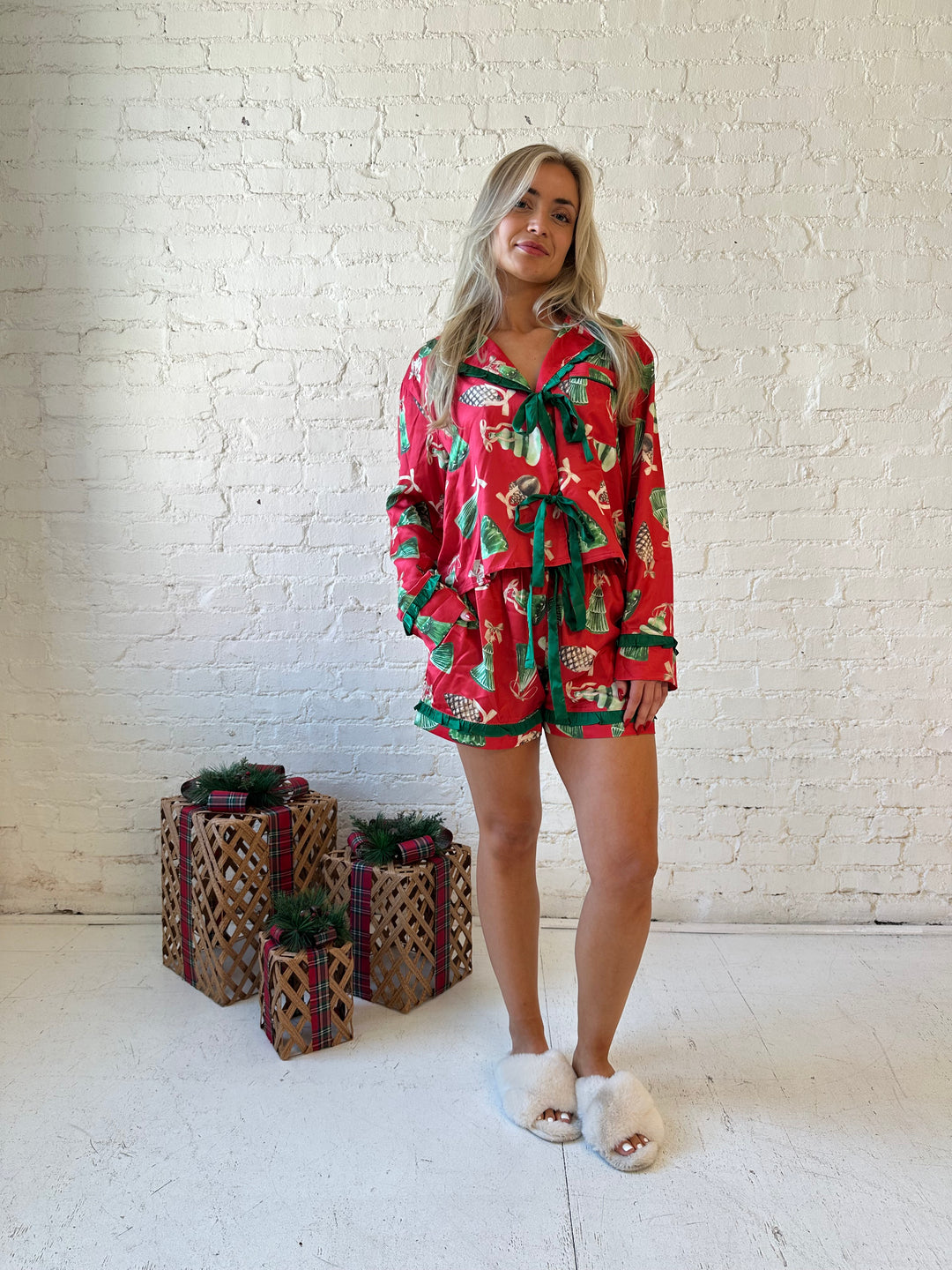 Woman wearing red satin pajama set with ornaments all over.