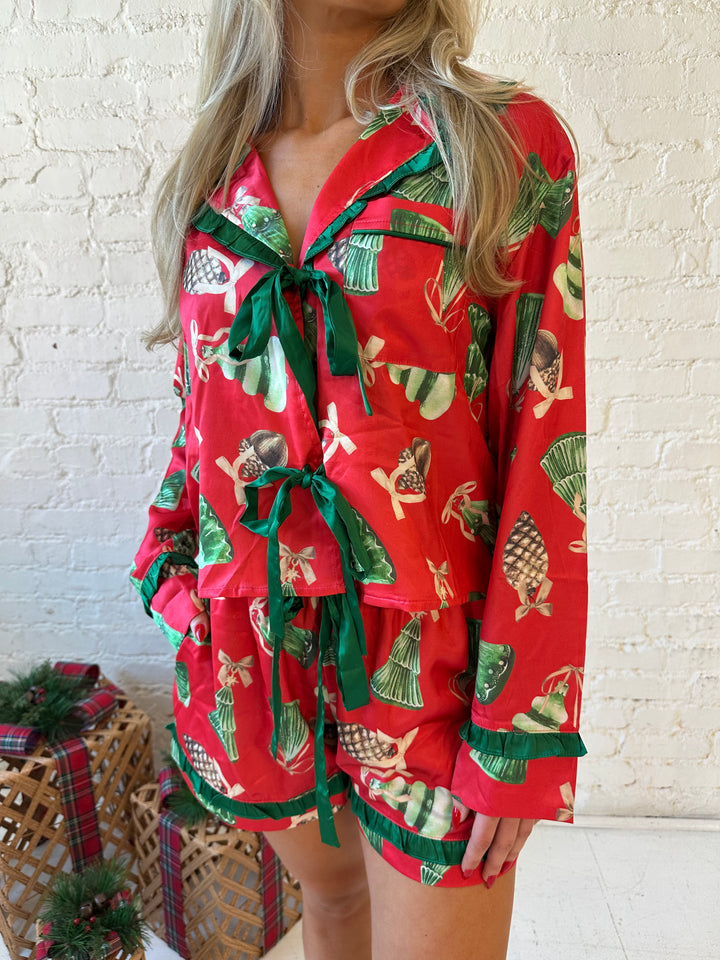 Woman wearing red satin pajama set with ornaments all over.