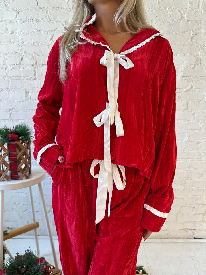 Woman wearing red velvet pajama set with long sleeve, and front tie closure. 