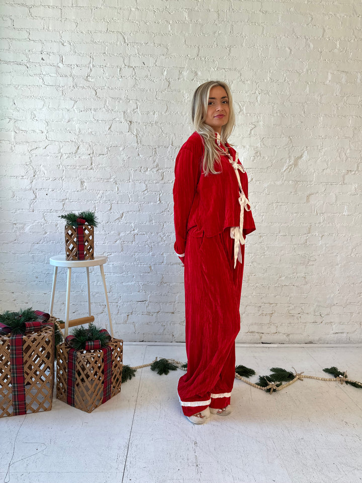 Woman wearing red velvet pajama set with long sleeve, and front tie closure. 