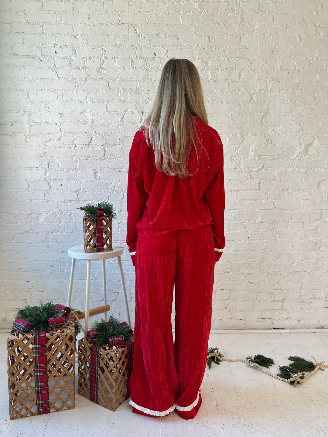 Woman wearing red velvet pajama set with long sleeve, and front tie closure. 