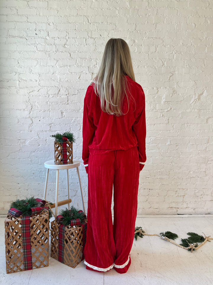 Woman wearing red velvet pajama set with long sleeve, and front tie closure. 