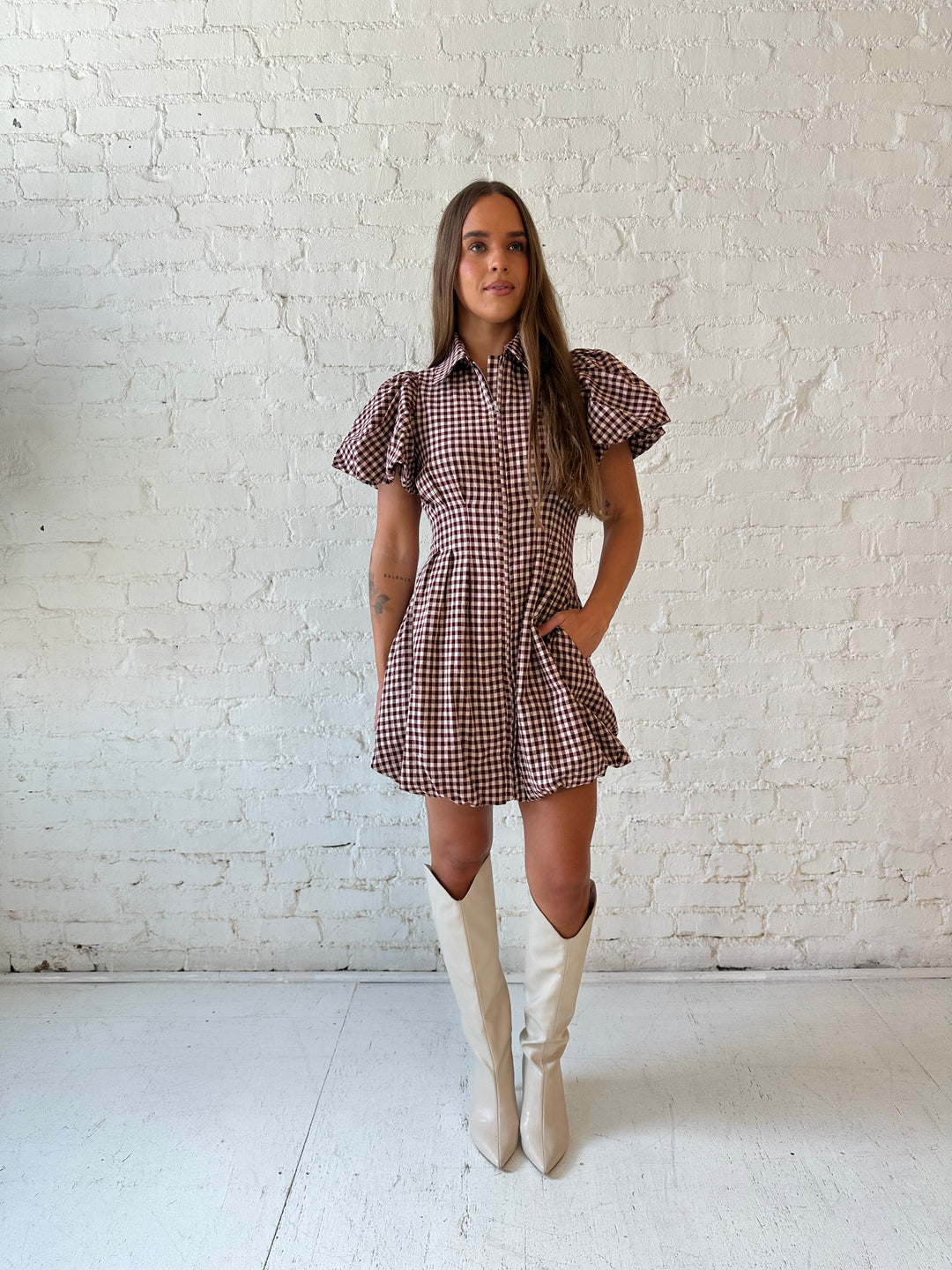 Woman wearing burgundy plaid mini dress with collar zipper neckline, short sleeves, and bubble hem.