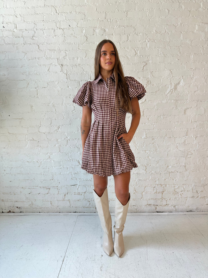 Woman wearing burgundy plaid mini dress with collar zipper neckline, short sleeves, and bubble hem.