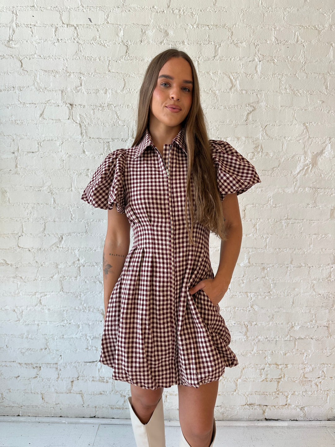 Woman wearing burgundy plaid mini dress with collar zipper neckline, short sleeves, and bubble hem.
