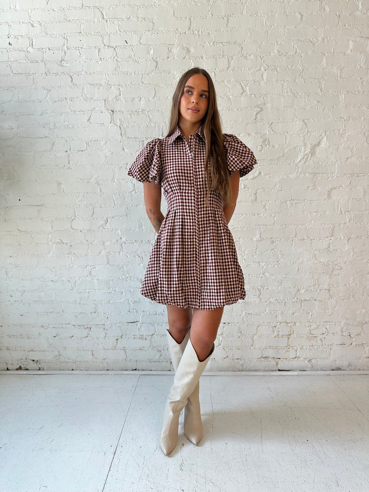 Woman wearing burgundy plaid mini dress with collar zipper neckline, short sleeves, and bubble hem.