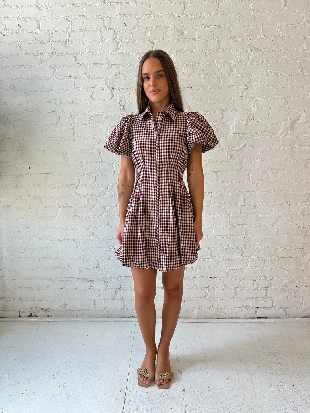 Woman wearing burgundy plaid mini dress with collar zipper neckline, short sleeves, and bubble hem.