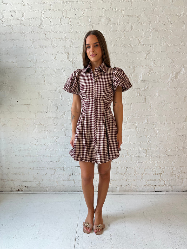 Woman wearing burgundy plaid mini dress with collar zipper neckline, short sleeves, and bubble hem.