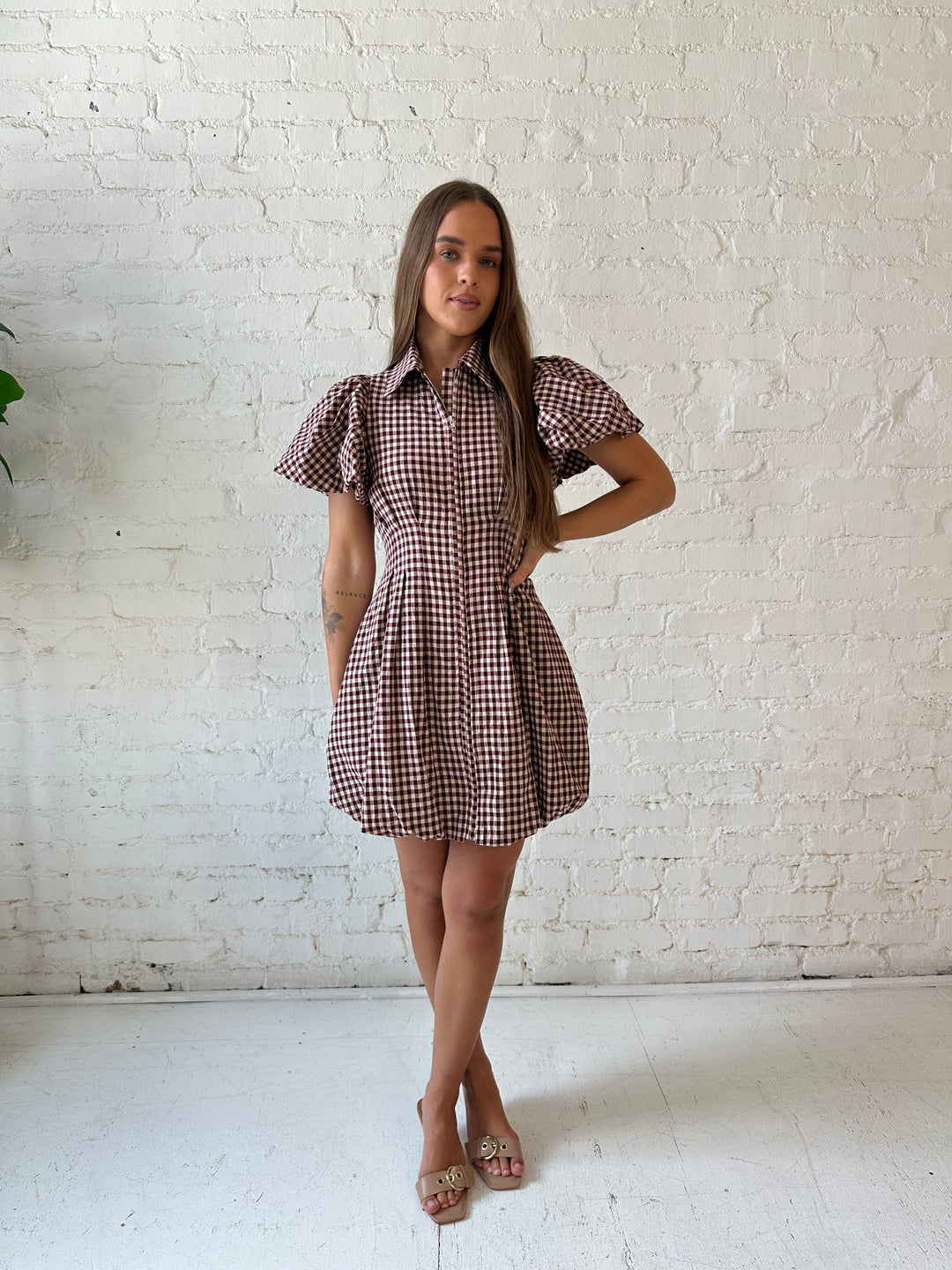Woman wearing burgundy plaid mini dress with collar zipper neckline, short sleeves, and bubble hem.