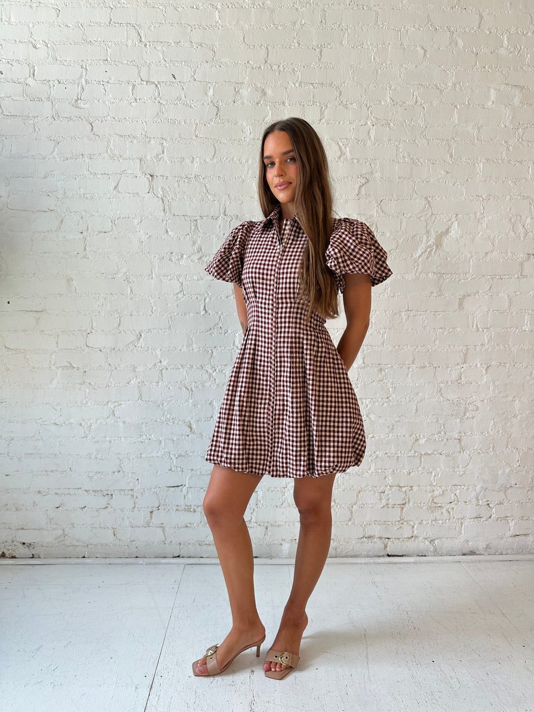 Woman wearing burgundy plaid mini dress with collar zipper neckline, short sleeves, and bubble hem.