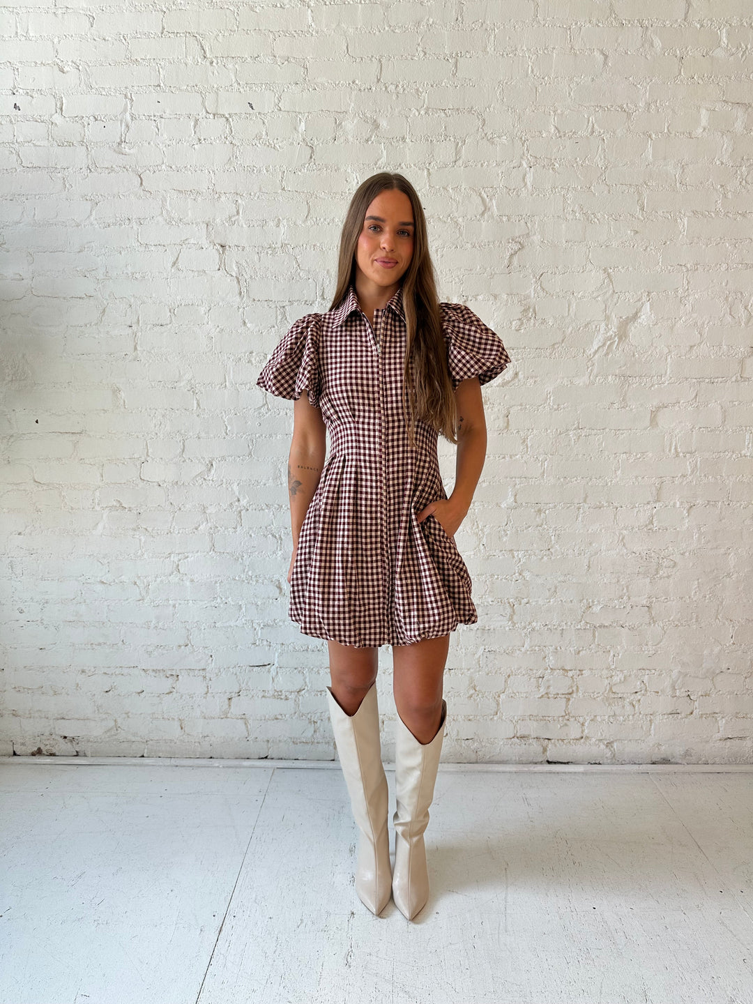 Woman wearing burgundy plaid mini dress with collar zipper neckline, short sleeves, and bubble hem.