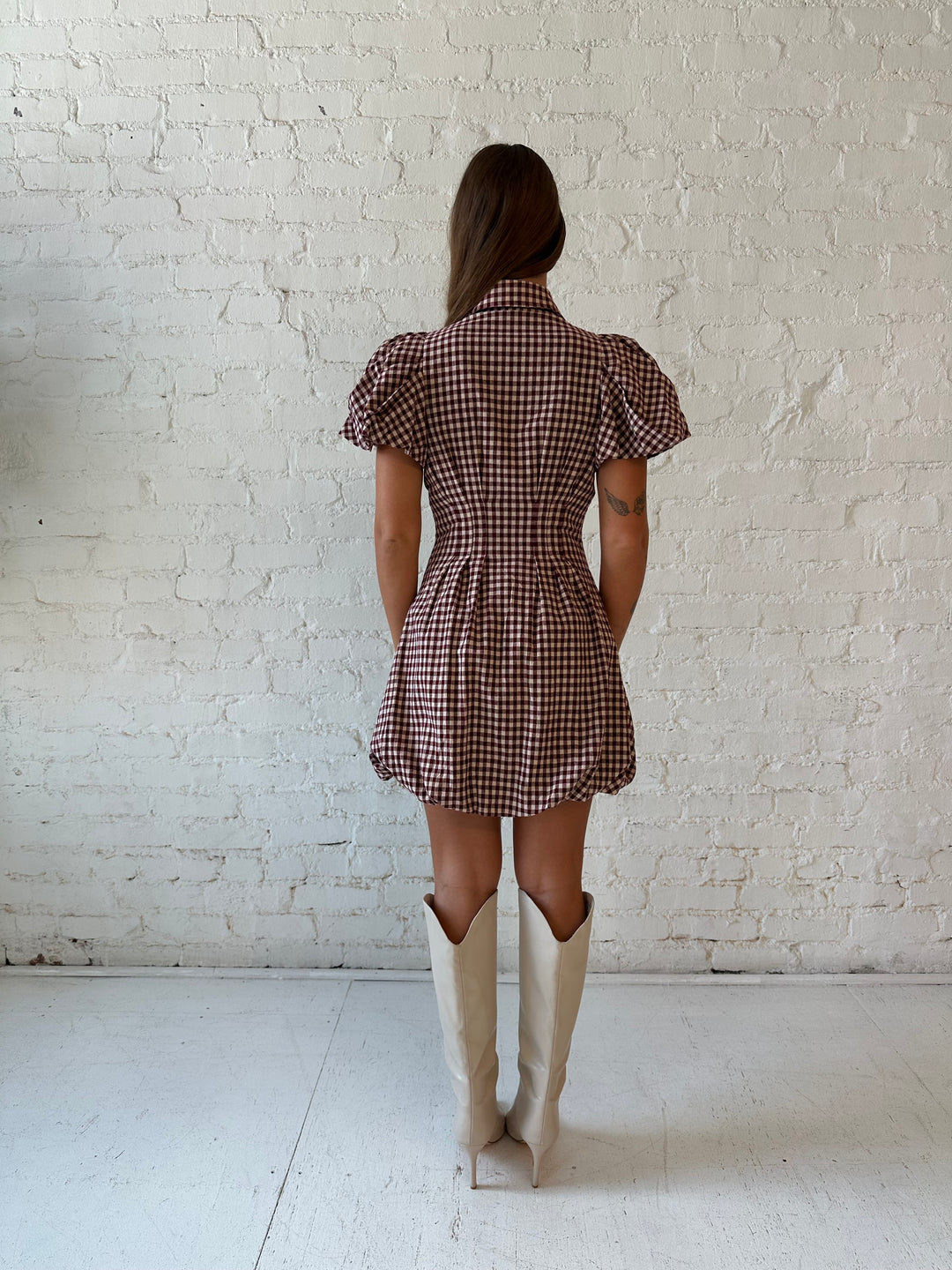 Woman wearing burgundy plaid mini dress with collar zipper neckline, short sleeves, and bubble hem.