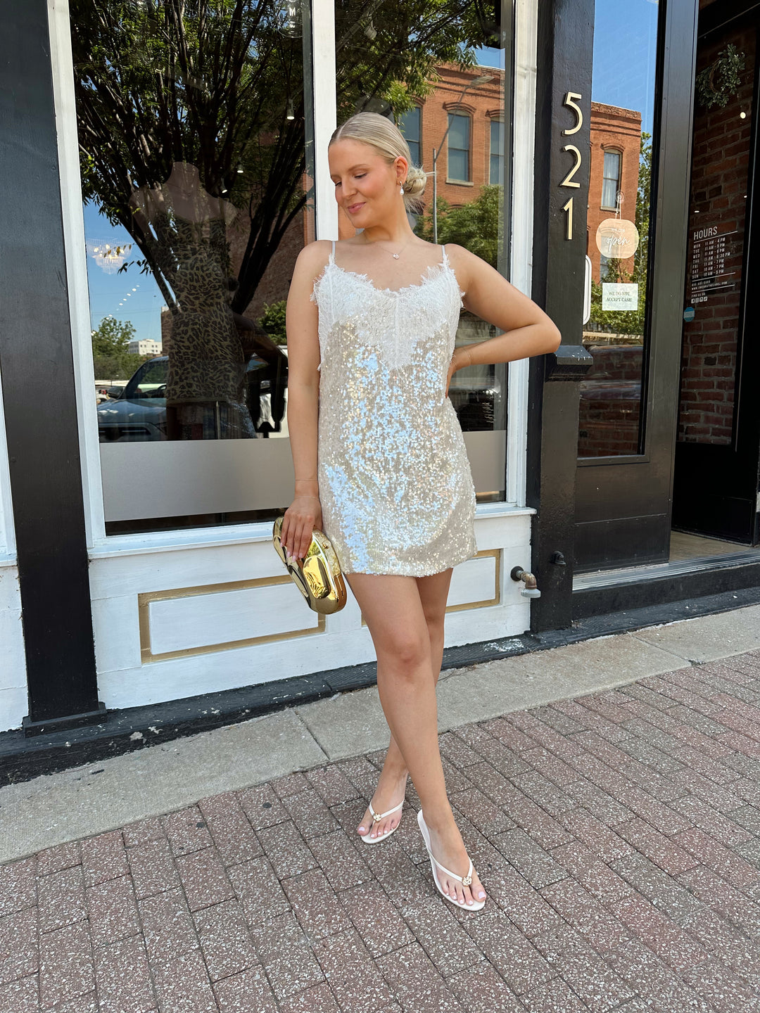 Woman wearing yellow sequin shift dress with lace trim neckline, and adjustable spaghetti traps.
