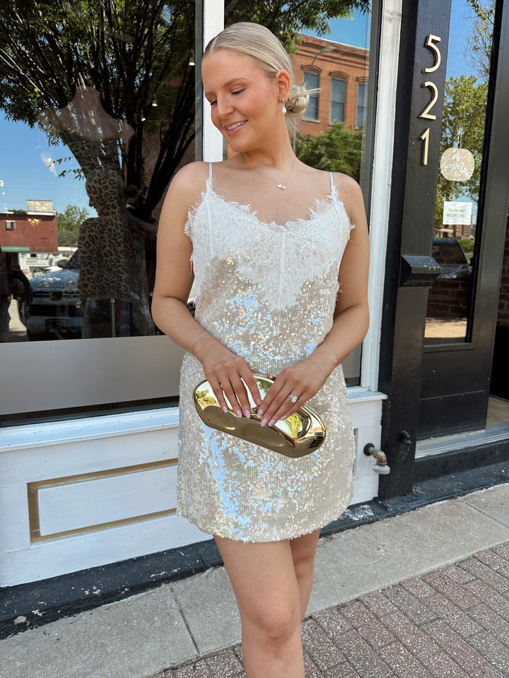 Woman wearing yellow sequin shift dress with lace trim neckline, and adjustable spaghetti traps.