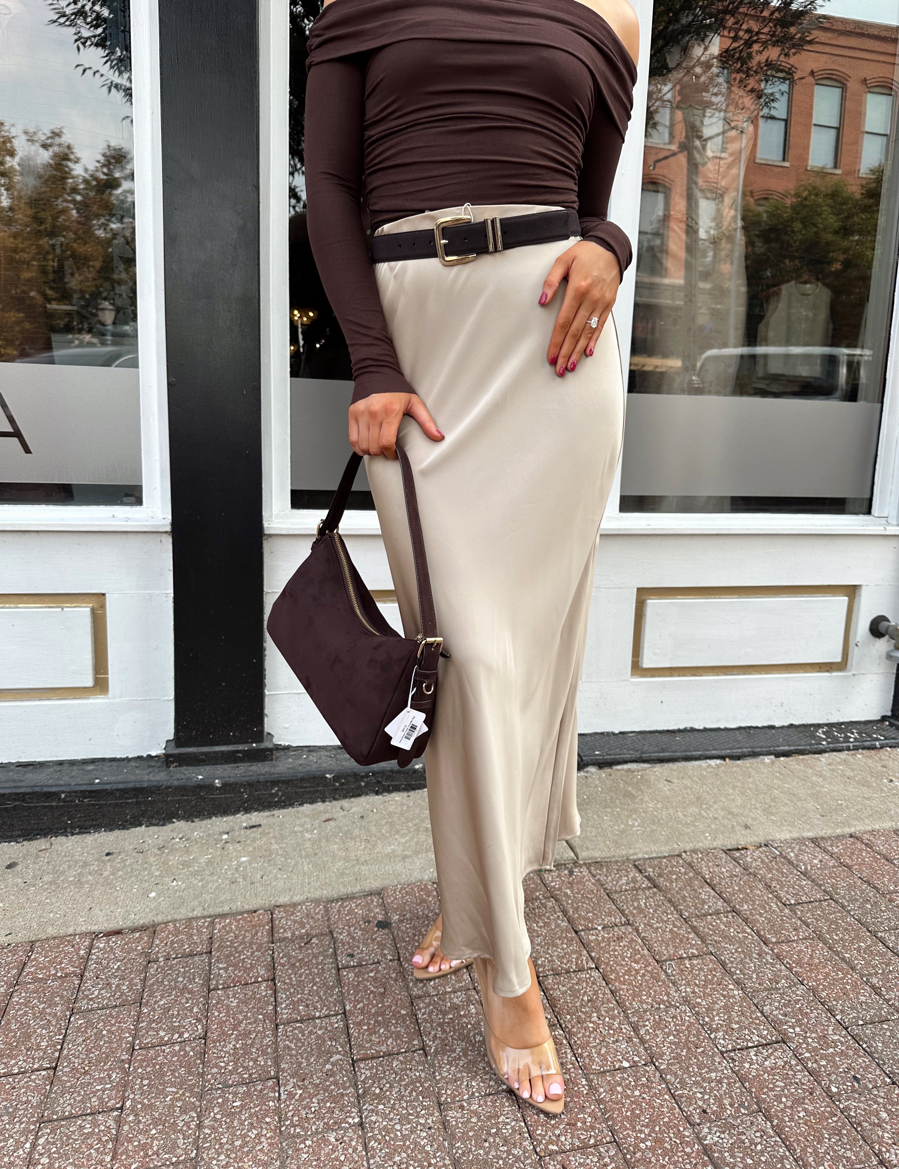 Woman wearing tan satin maxi skirt with elastic waist band and brown off the shoulder bodysuit.