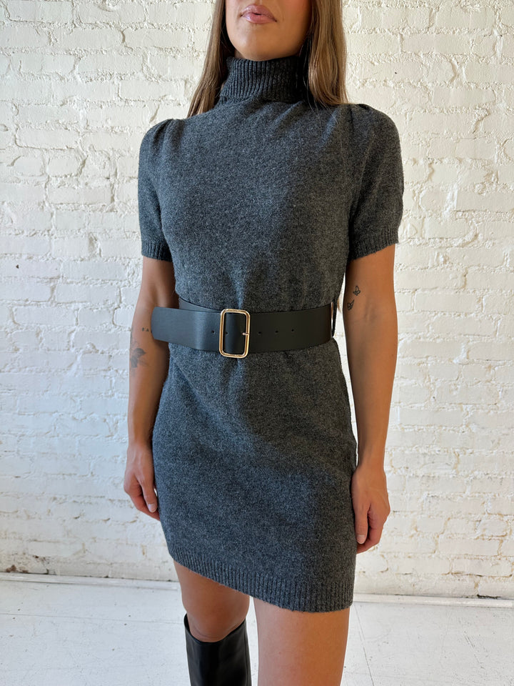 Woman wearing charcoal grey knit mini dress with belted waist, and puff sleeve detailing, with suede knee boots. 