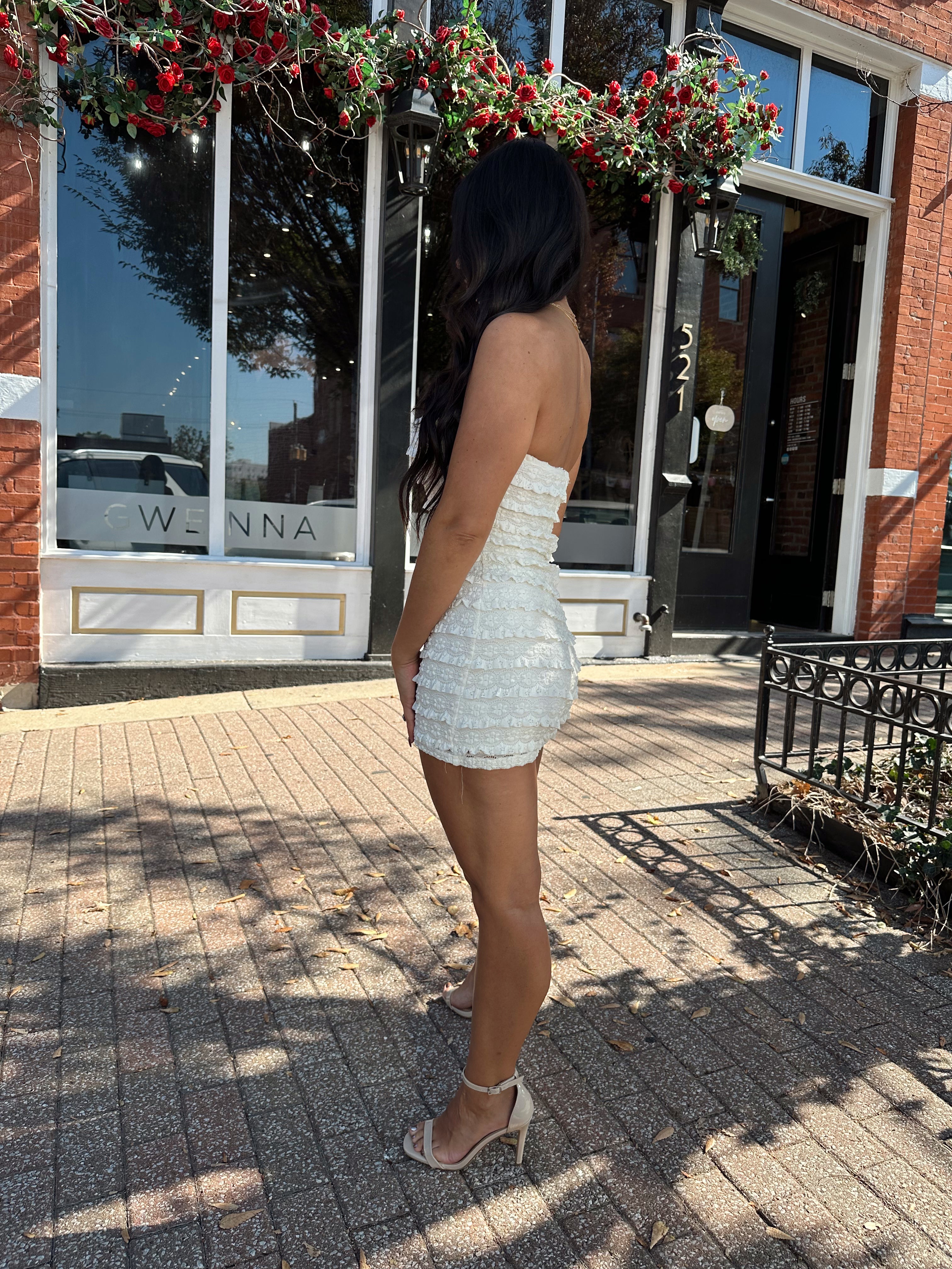 Woman wearing ivory textured strapless romper with brown leather blazer.