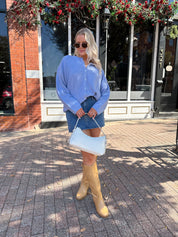 Woman wearing baby blue knit button down cardigan with denim skirt. 
