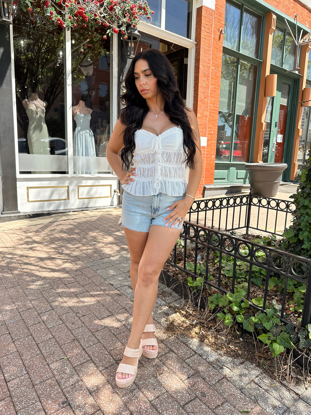 Woman wearing white tiered tank top with adjustable straps.