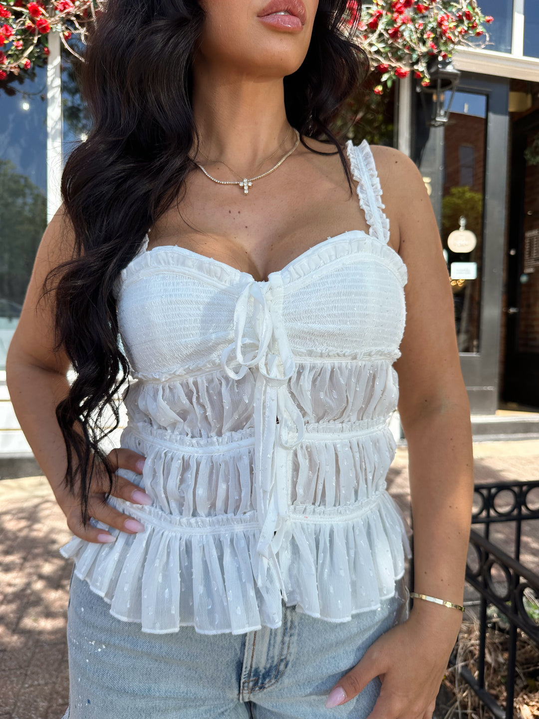 Woman wearing white tiered tank top with adjustable straps.