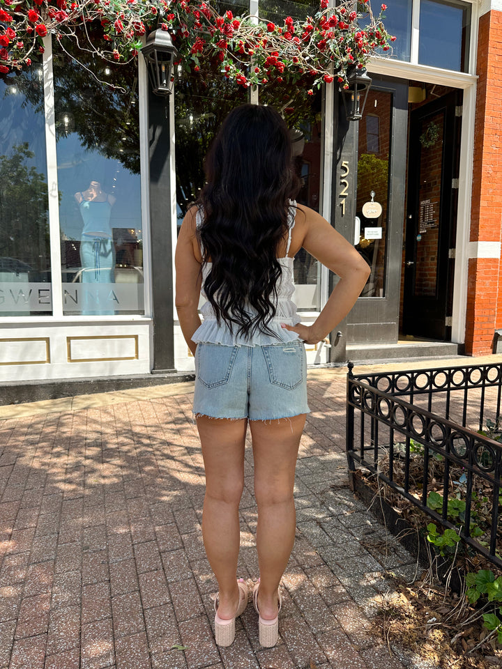 Woman wearing white tiered tank top with adjustable straps.