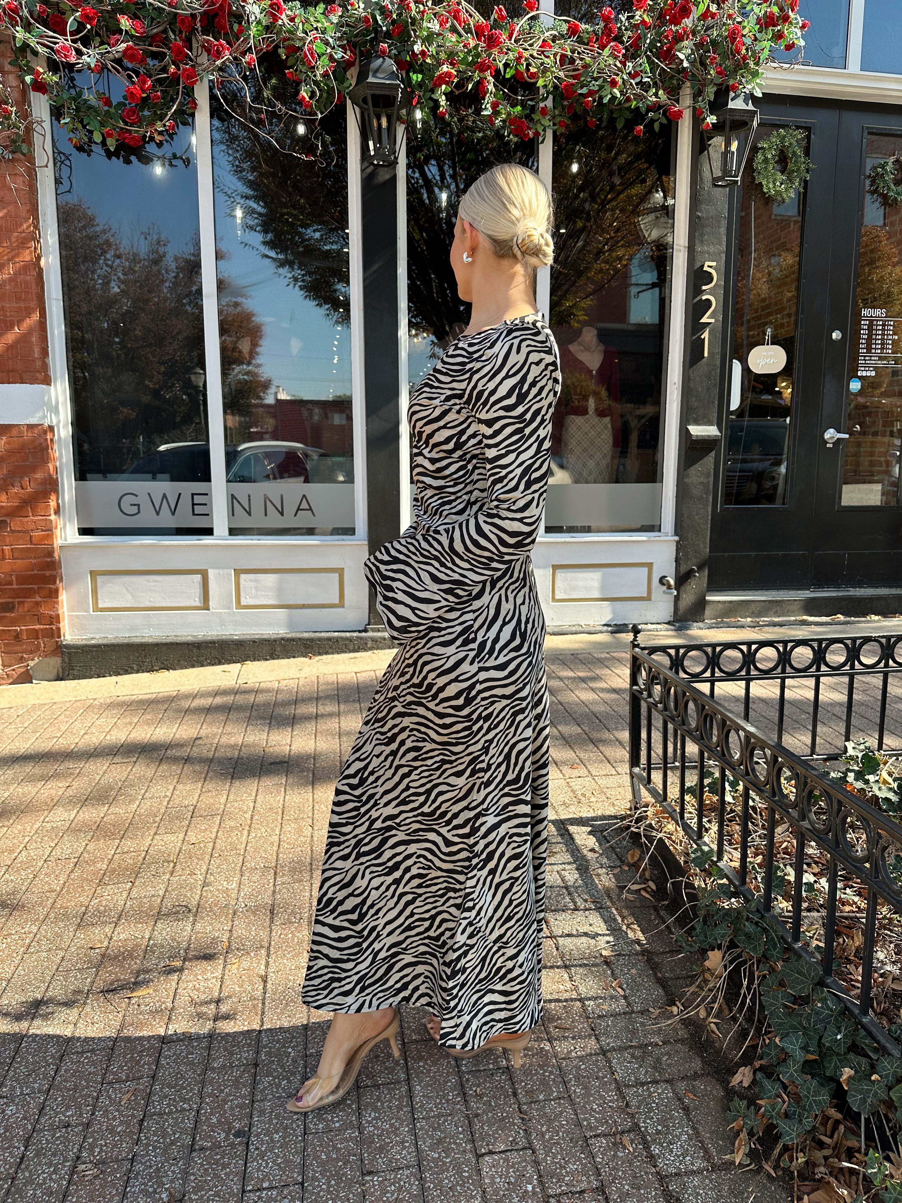 Woman wearing long sleeve zebra print maxi dress with wide sleeve.