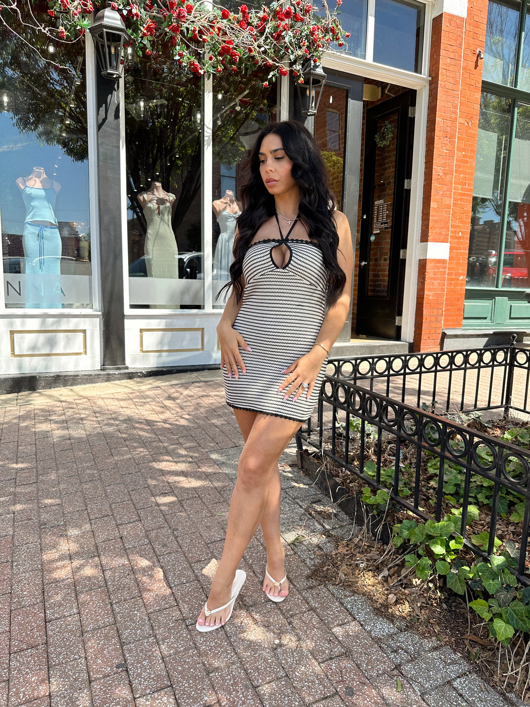 Woman wearing black and neutral striped crochet mini dress with a self tie halter neck.  