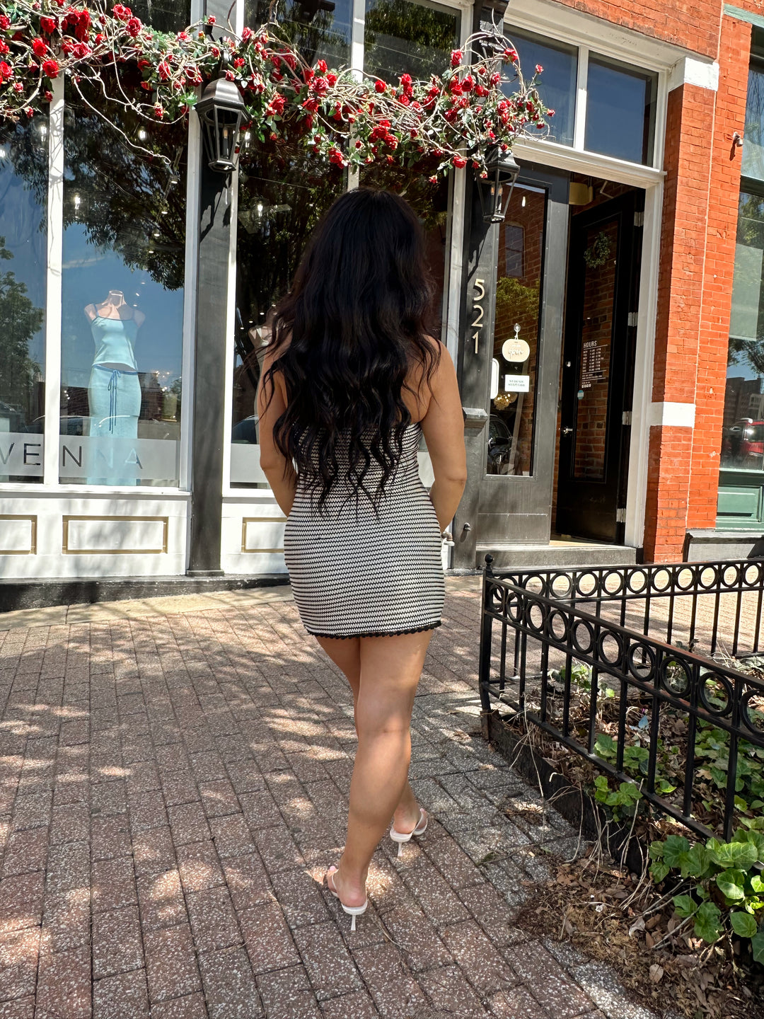 Woman wearing black and neutral striped crochet mini dress with a self tie halter neck.  