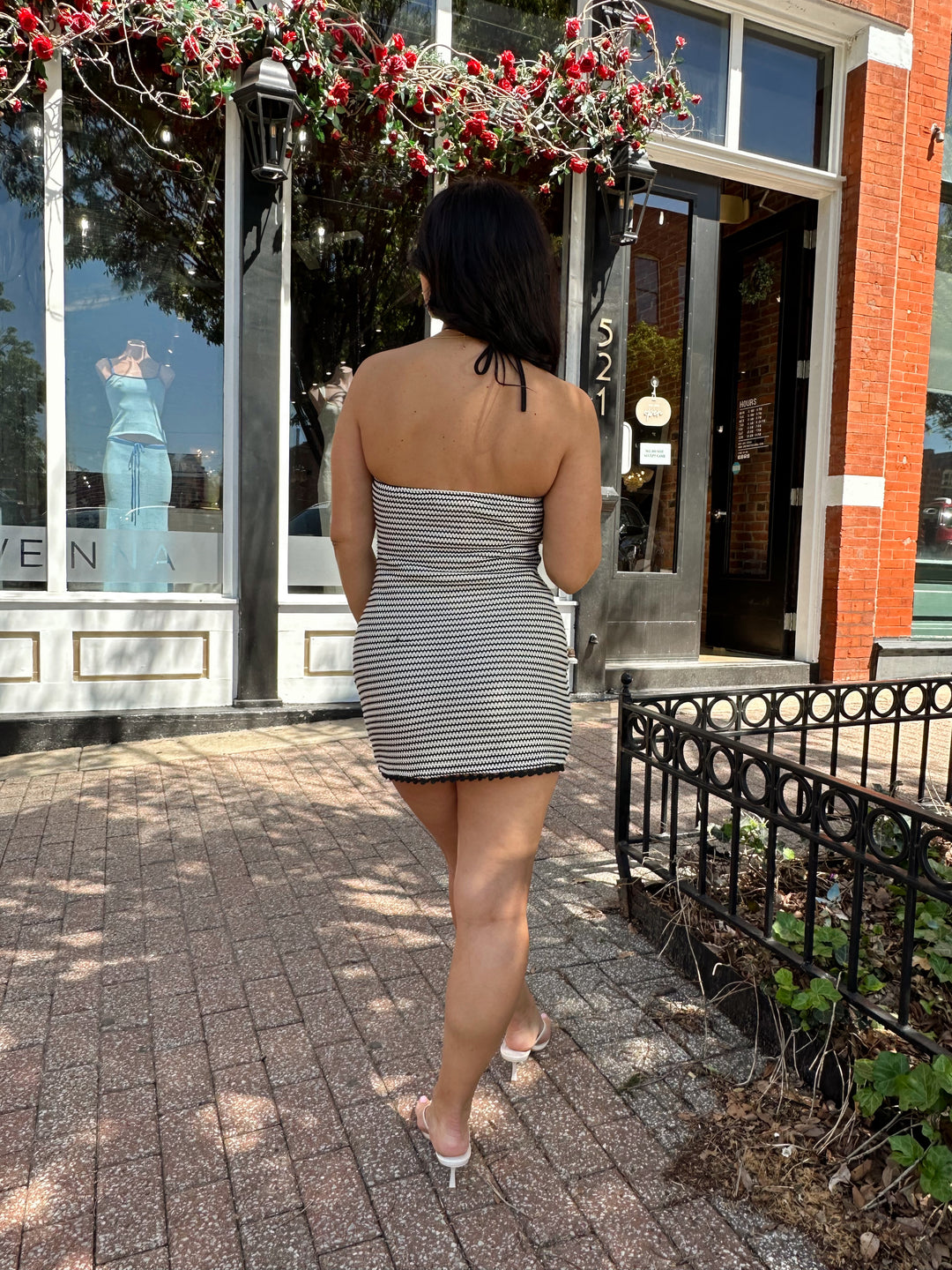 Woman wearing black and neutral striped crochet mini dress with a self tie halter neck.  