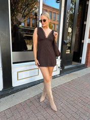 Model wearing brown eyelet lace mini dress with open back and scalloped trim.