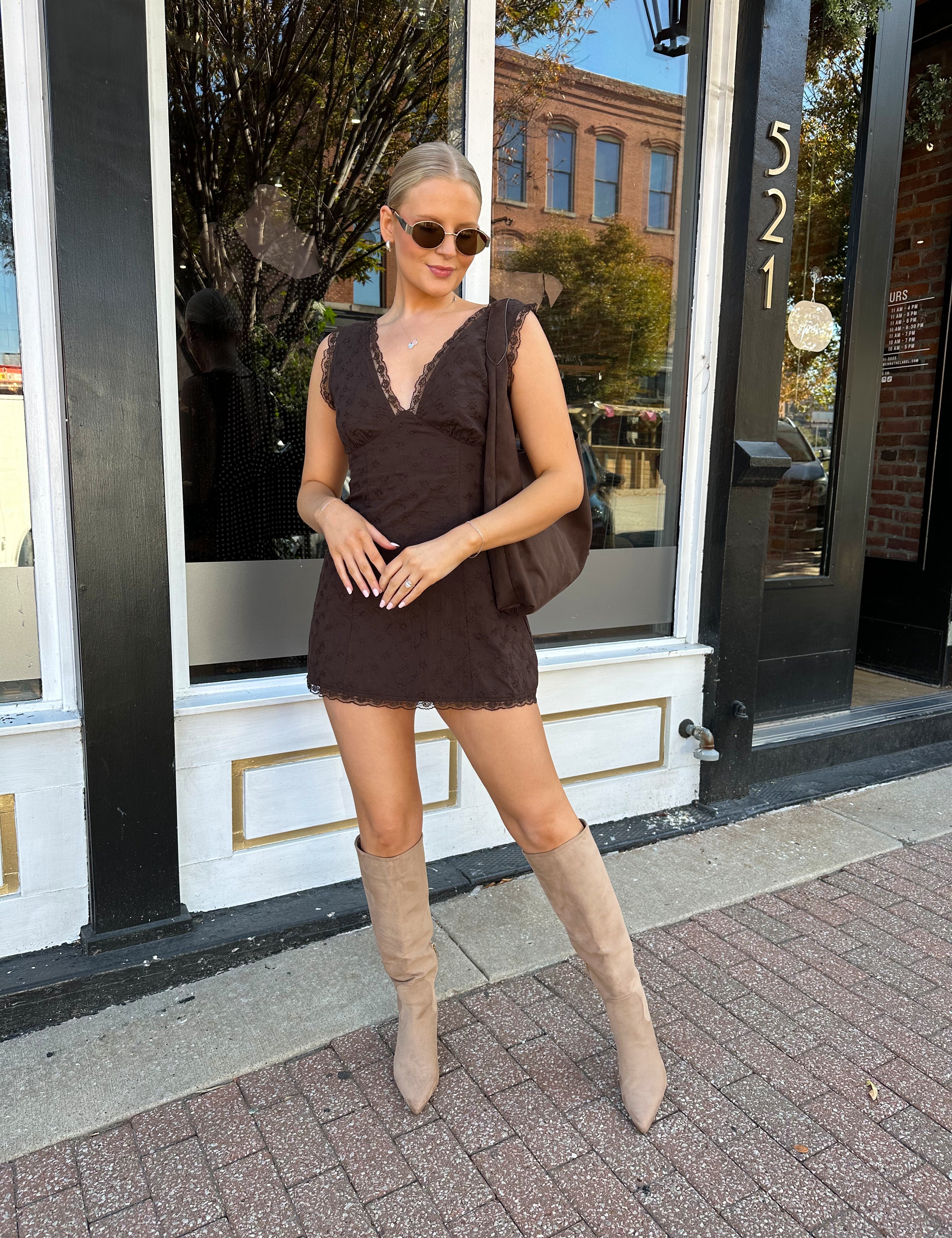 Model wearing brown eyelet lace mini dress with open back and scalloped trim.