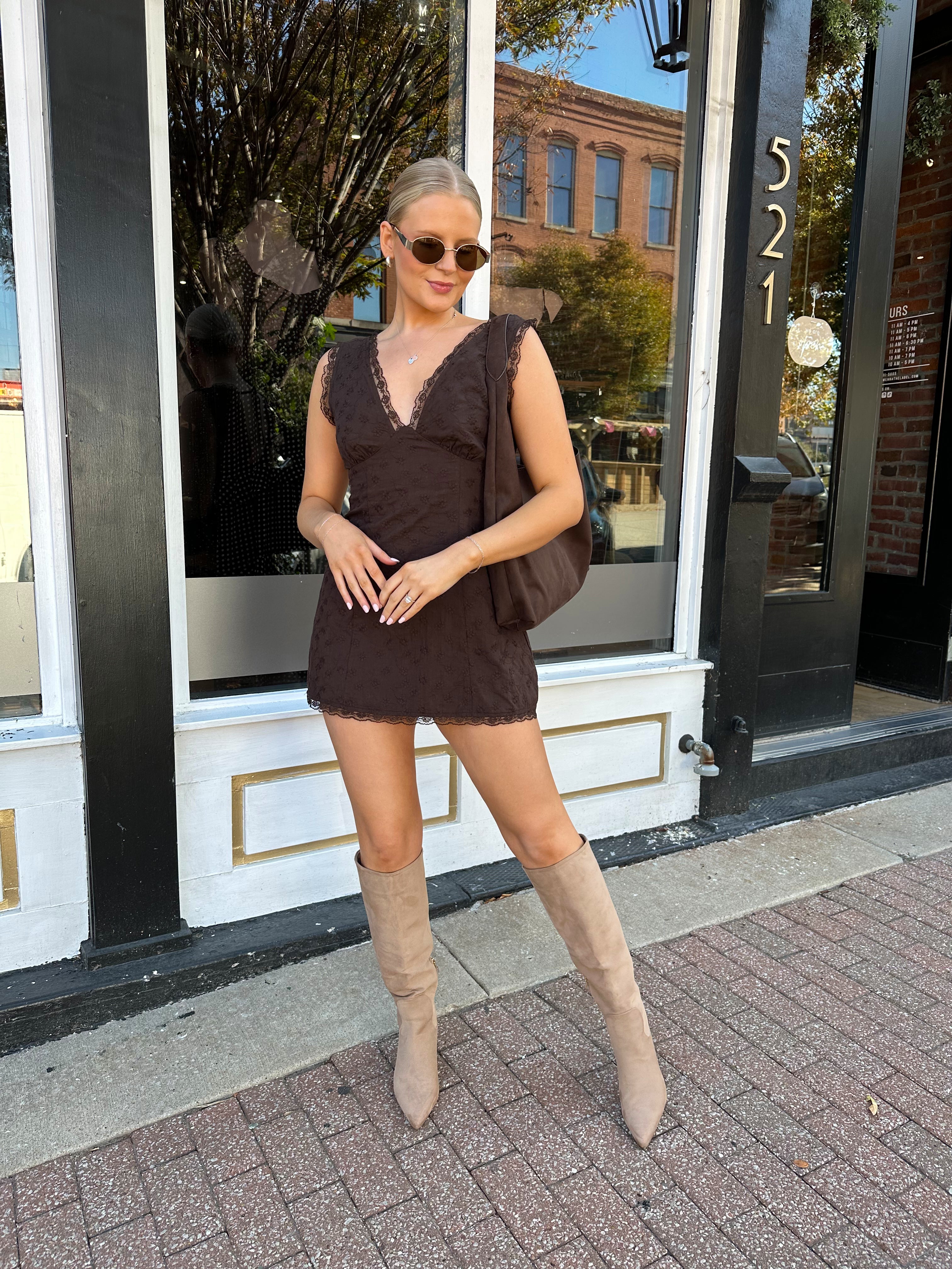 Model wearing brown eyelet lace mini dress with open back and scalloped trim.