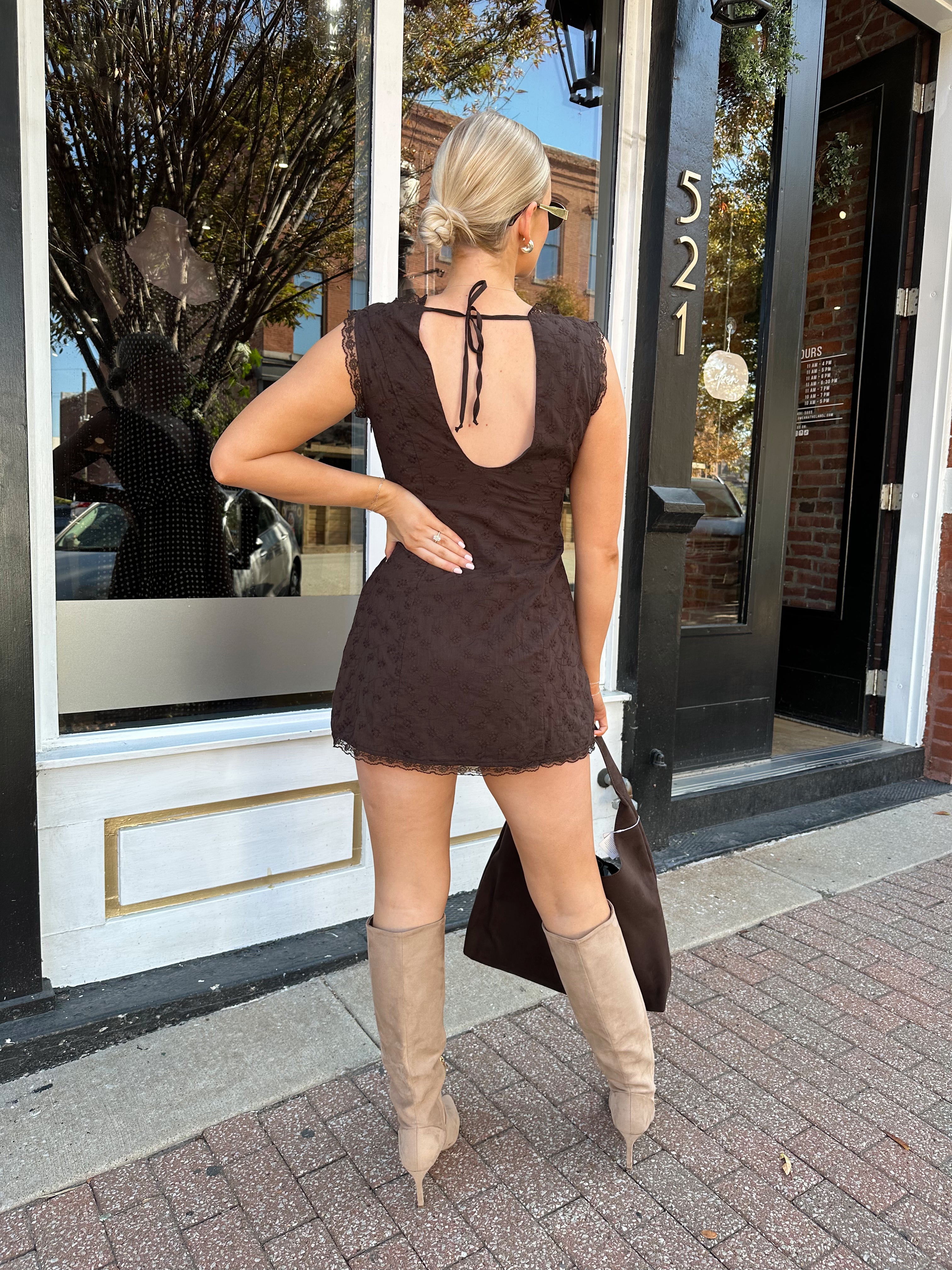 Model wearing brown eyelet lace mini dress with open back and scalloped trim.