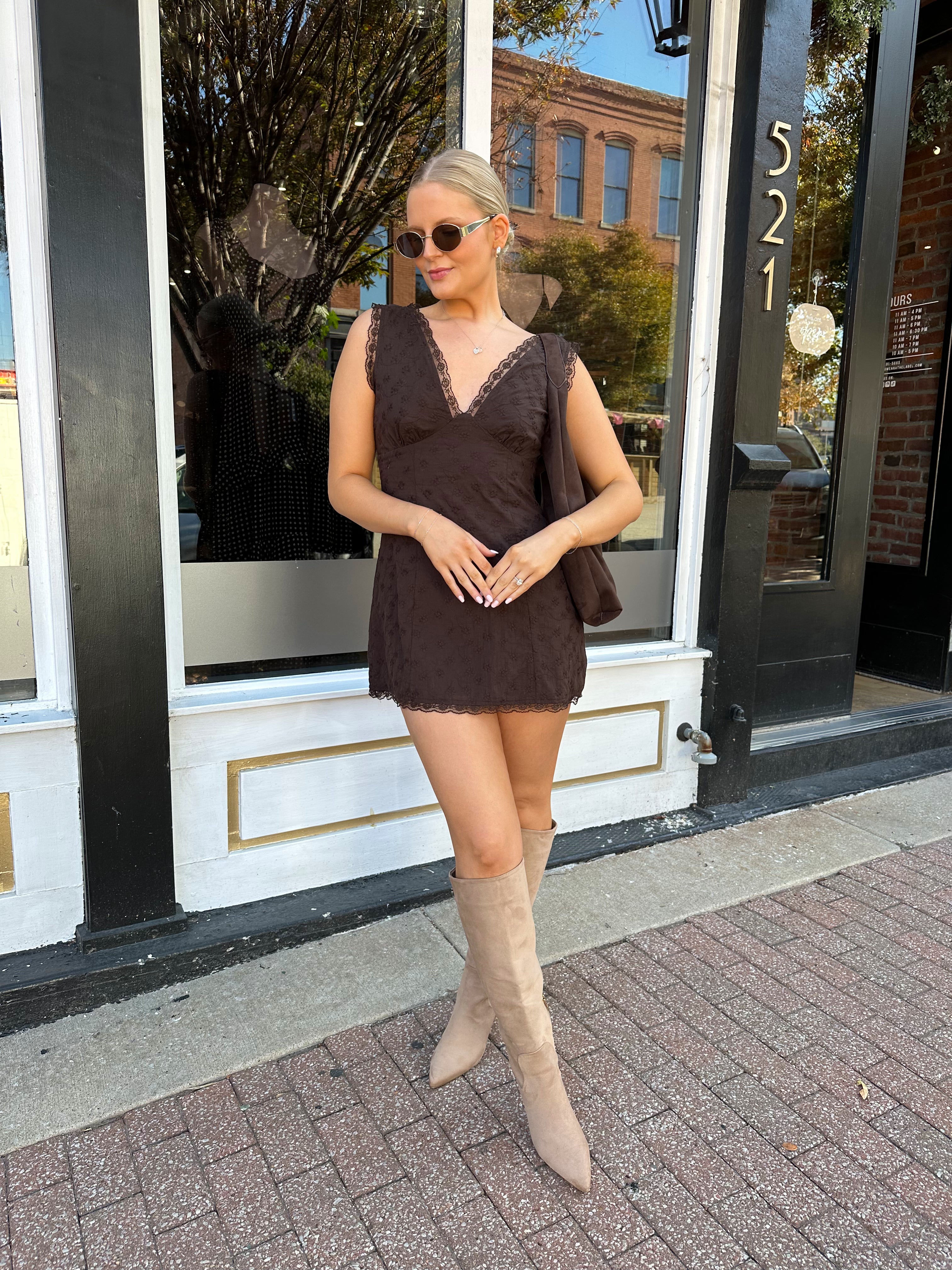 Model wearing brown eyelet lace mini dress with open back and scalloped trim.