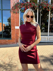 Woman wearing burgundy knit mock neck mini dress with leather trench coat.
