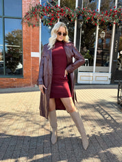 Woman wearing burgundy knit mock neck mini dress with leather trench coat.