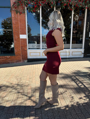 Woman wearing burgundy knit mock neck mini dress with leather trench coat.