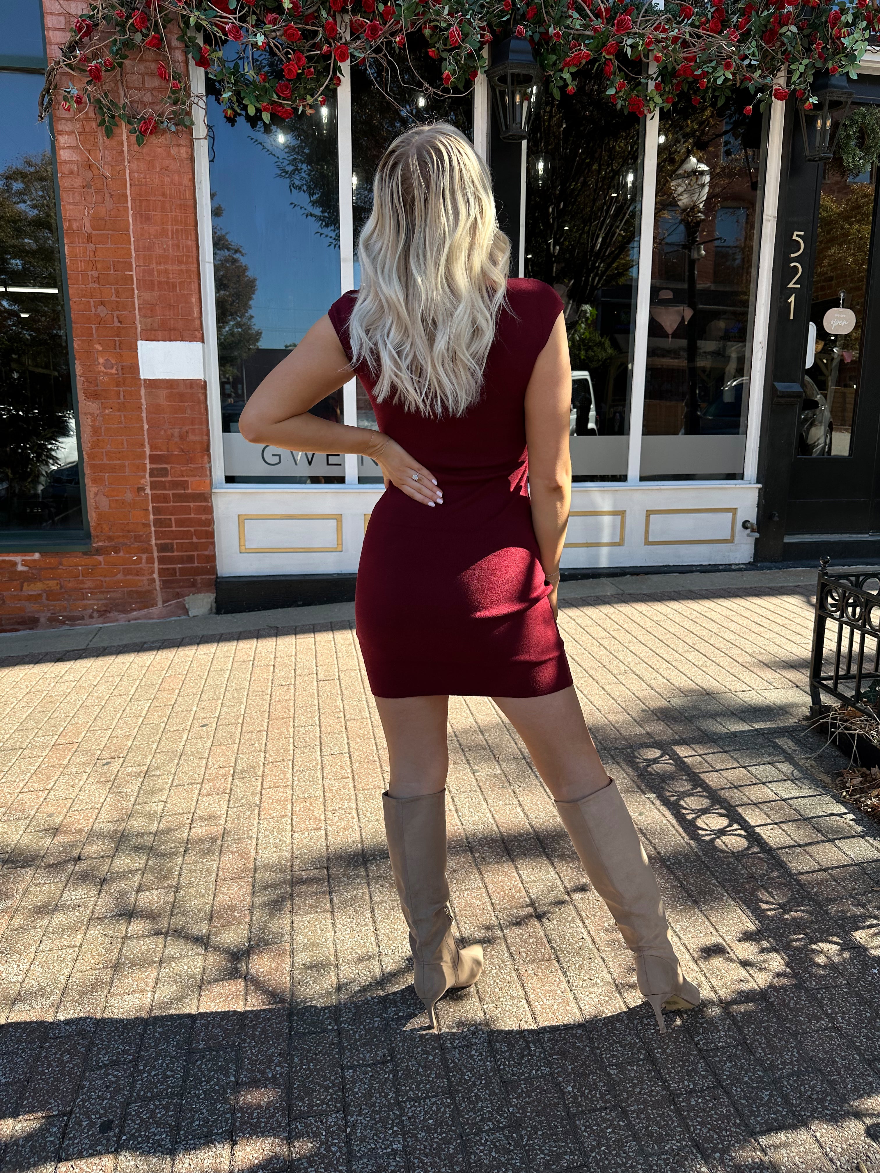 Woman wearing burgundy knit mock neck mini dress with leather trench coat.