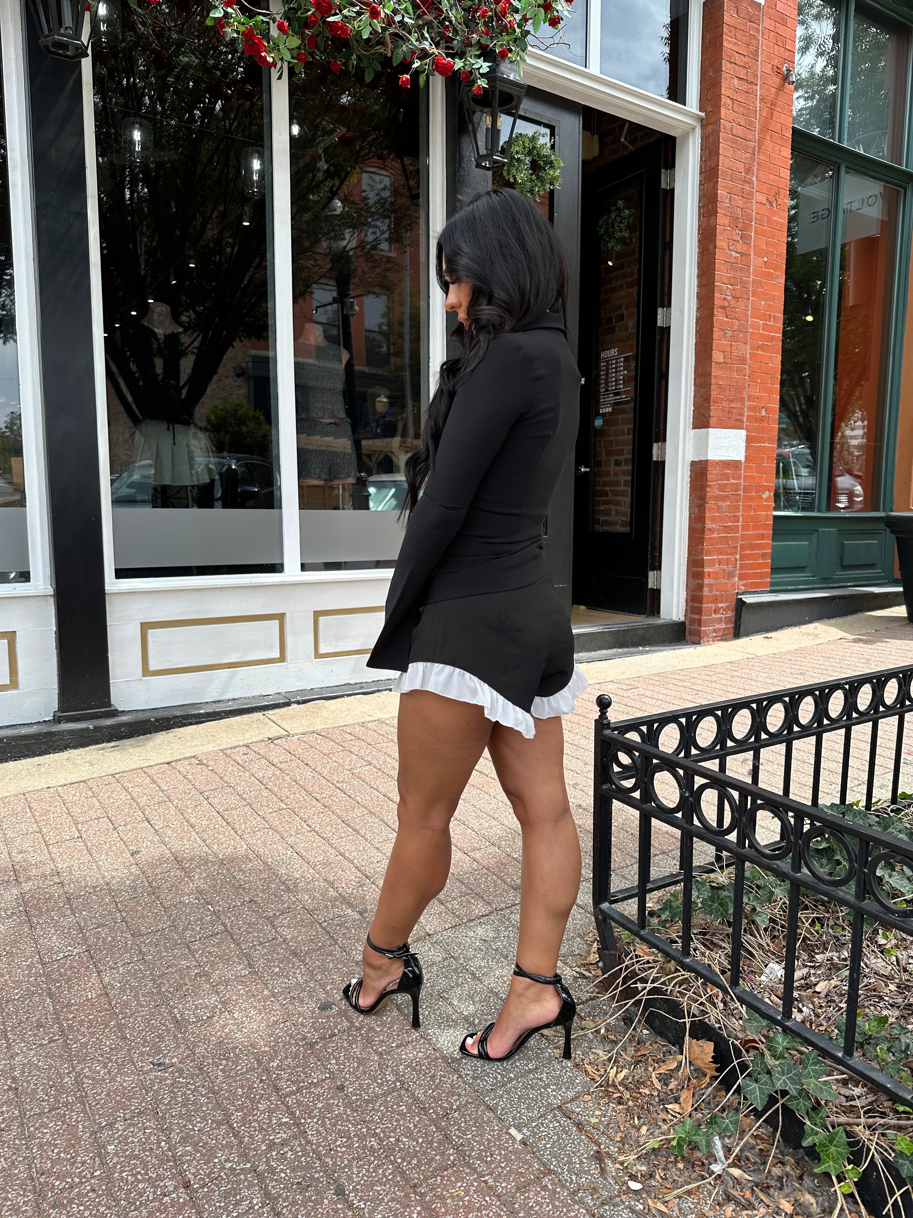 Woman wearing black shorts with white ruffle hem. 
