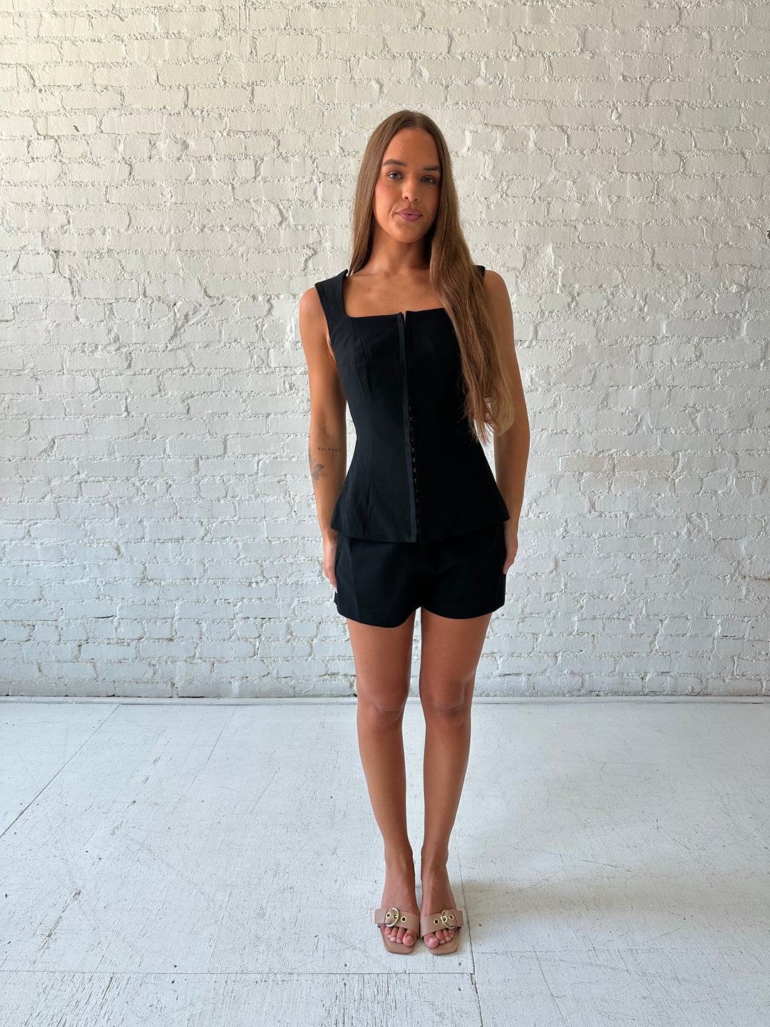 Woman wearing black tailored two piece set with front clasp closure.