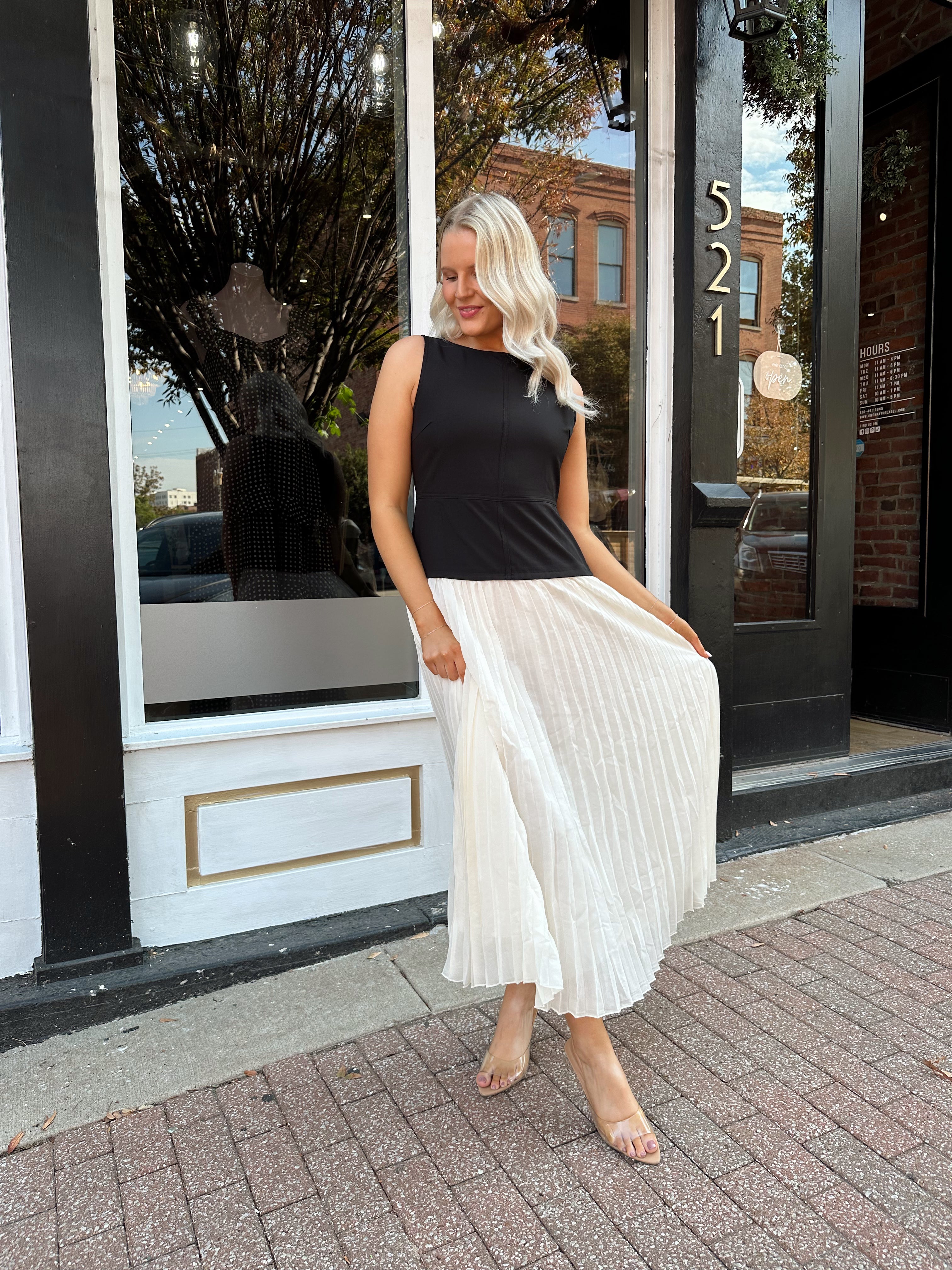 Woman wearing contrast midi dress with black top and cream pleated skirt. 
