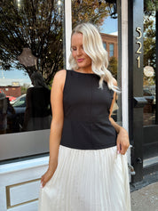 Woman wearing contrast midi dress with black top and cream pleated skirt. 