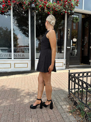 Woman wearing black polka dot mini dress with black blazer over top.