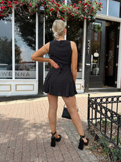 Woman wearing black polka dot mini dress with black blazer over top.