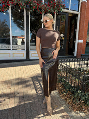 Woman wearing brown knit short sleeve sweater top with bow back.